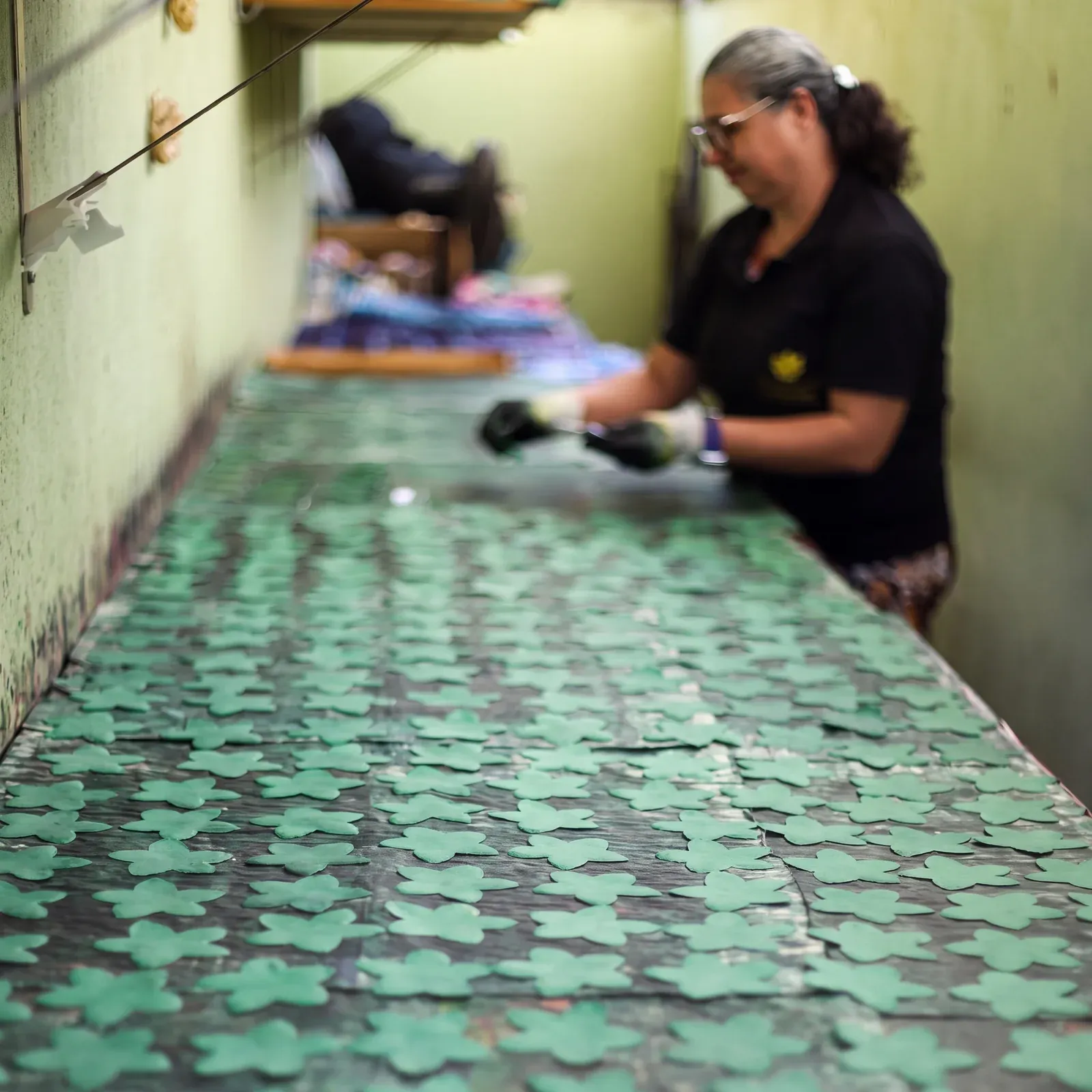 Artesã da Embalarte finalizando forminhas verdes sobre a mesa de produção no ateliê em Floresta, Belo Horizonte