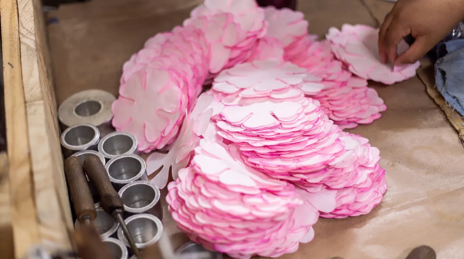 Pilhas de pétalas rosa recém-cortadas ao lado das fôrmas de alumínio, no ateliê da Embalarte em Floresta, Belo Horizonte